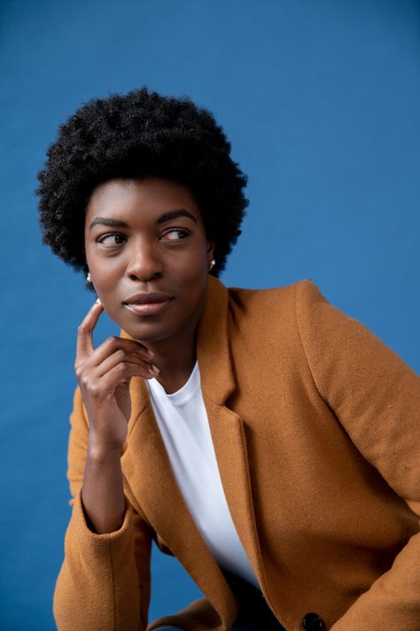 A black girl smirking while wearing a afro, a white T shirt and tan peacoat Creative Professional Photoshoot, Creative Professional Headshots, Colorful Headshots, Bright Color Background, Fun Headshots, Headshot Wardrobe, Corporate Shoot, Modeling Headshots, Commercial Headshots