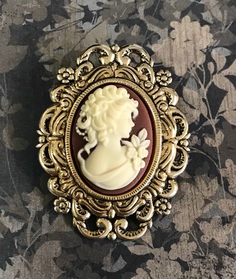 Cameo brooch. A dimensional cameo brooch with antiqued gold plated settings with a layed effect. The pretty resin cameo is rust brown and creme. The pinback has a bail so it can also be worn as a pendant. This piece measures 1 3/4 inches long. This would make a great cameo lover gift. A gift box is included. Antique Cameo Brooch, Vintage Brooch, Gold Cameo Brooch For Wedding, Cameo Tattoo, Formal Gold Cameo Brooch, Elegant Black Cameo Brooches, Elegant Gold Cameo Brooch, Blue Anklet, Gold Cameo Brooch Collectible