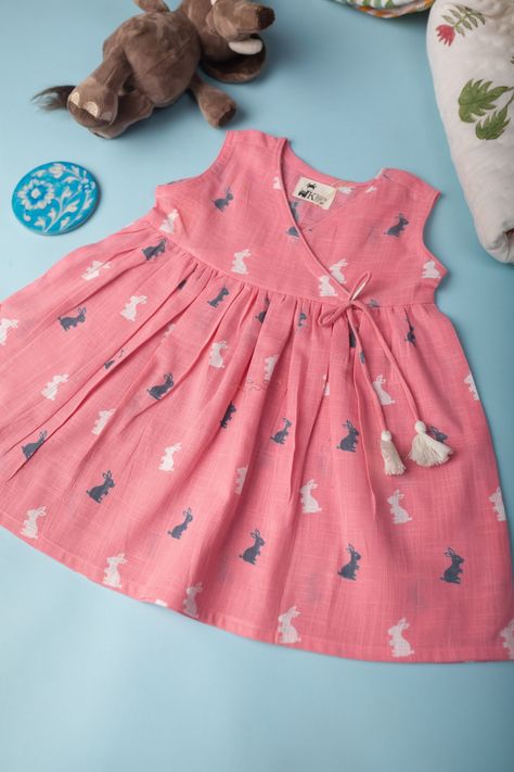 This baby pink kids cotton slub frock is a charming and cute choice for any child’s wardrobe. It features handmade tassels on the side, which adds a playful and unique touch to the design. The frock also has an adorable rabbit print, which is sure to delight any child. The frock has an angrakha neck, which is a traditional and elegant style that adds sophistication to the design. With a sleeveless design, this frock is perfect for warm weather and outdoor play. Made from soft and comfortable cot Cotton Frocks For Kids, Frocks For Kids, Kids Party Wear Dresses, Frock Designs, Kids Dress Collection, Cotton Frocks