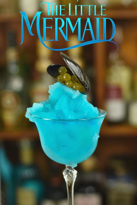 bright blue frozen margarita with weird garnish for a little mermaid themed cocktail. text on screen saying little mermaid. weird sea themed garnish Ocean Theme Cocktail, Disney Mocktail Recipe, Mermaid Margarita, Mermaid Recipes, Disney Themed Drinks, Disney Alcoholic Drinks, Cocktail Contest, Frozen Margarita Recipe, Alcoholic Milkshake