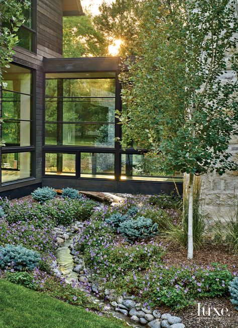 Hubbard created a bridge under the elevated glass hallway between the main house and the garage so the stream that runs through the property could also flow under the structure. Landscape architect Luke Sanzone lined the waterway with evergreen shrubs and Rozanne geraniums. Surround Architecture, Barn House Design, Modern Barn House, Modern Farmhouse Exterior, The Rocky Mountains, Barn Style House, Luxe Interiors, Modern Barn, Farmhouse Exterior