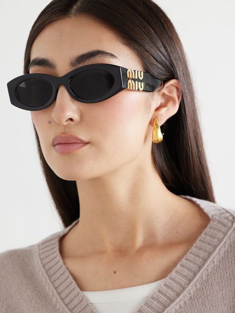 Miu Miu’s ‘Glimpse’ sunglasses embrace ‘90s style with a contemporary update. Made from black acetate, they have oval frames with smoked lenses. The wide arms are decorated with exaggerated gold-tone logos, which double as hinges. Mui Mui Sunglasses, Fashion Glasses For Women, Miu Miu Glasses, Glasses Outfit, Miu Miu Sunglasses, Trendy Glasses, Glasses For Women, Butterfly Sunglasses, Summer Sunglasses