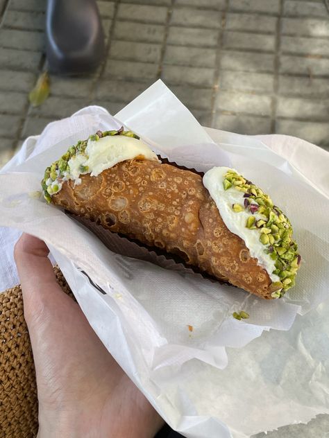 Hand holding an Italian cannoli dessert with pistachio crust Italian Food In Italy, Cannoli Pistachio, Cannoli Aesthetic, Pistachio Cannoli, Dessert Cannoli, Italian Aperitivo, Italian Sweets, Italian Street Food, Italian Pastries