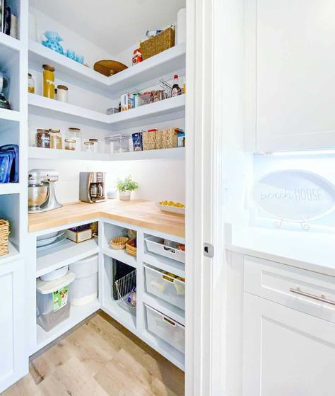 Enjoy a walk-in pantry that features white corner shelves, making items easily accessible. A butcher's block countertop provides space to store kitchen appliances. Add extra storage by installing cubbies beneath the countertop. Short Floating Shelves, Butchers Block Countertop, Corner Walk In Pantry, Floating Pantry Shelves, Walk In Pantry With Countertop, Pantry With Countertop, White Corner Shelves, Functional Pantry, White Corner Shelf