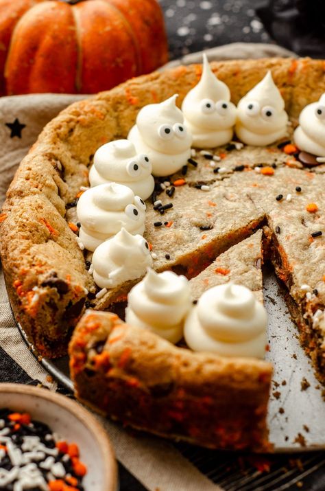 Turn any cookie cake into a Halloween spectacle with simple frosting ghosts. This easy Halloween cake recipe features chocolate chips and festive sprinkles for a fun Halloween cookie cake for kids and adults alike. This is a great option for Halloween potluck ideas for work or a Halloween party dessert recipe. Everyone will want more of this Halloween chocolate chip cookie cake. | halloween cookie cake designs easy | halloween cookie cake recipe | how to make frosting ghosts Cake Recipes Halloween, Halloween Slice And Bake Cookies, Ghost Cookie Cake, Spooky Cheesecake, Halloween Baking Ideas Easy, Halloween Deserts Ideas, Halloween Potluck Ideas For Work, Halloween Themed Dessert, Pumpkin Cookie Cake