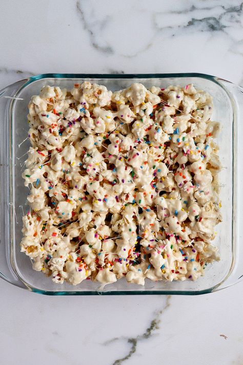 top down view of funfetti marshmallow popcorn treats in glass baking dish Cake Batter Popcorn Recipe, Marshmallow Puffcorn, Marshmallow Pretzel Treats, Marshmellow Popcorn Easy, White Chocolate Puffcorn, Popcorn Marshmallow Treats, Popcorn Fluff, Funfetti Popcorn Recipes, Marshmallow Christmas Treats