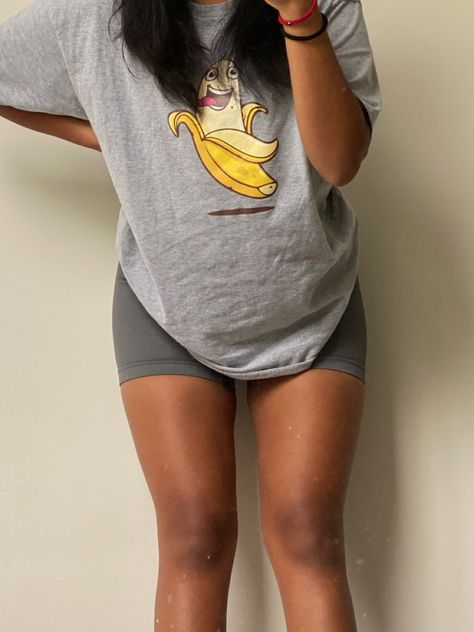 Evelyn wearing a grey oversized t shirt with a smiling banana in the middle and dark grey biker shorts. Big Tee And Shorts Outfit, Oversized Tee Gym Outfit, Big Shirt Gym Outfit, Gray Biker Shorts Outfit, Oversized Gym Outfit, Tshirt And Shorts Outfit, Shorts Gym Outfit, Summer Camp Outfits, Cycling Shorts Outfit