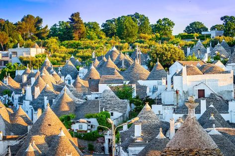 Dotting the countryside, their conical limestone roofs pop up amid the tall grass and trees, often sitting just behind low stone walls. The name for these curious little homes is “trullo” (the plural is trulli) and they’ve been a feature of Puglia’s Valle d’Itria on the heel of Italy’s boot for centuries. Legend has it that during the Medieval period when this area was ruled by feudal overlords, the peasants built these homes because they were easy to dismantle. When the tax collectors came, the Italy Alberobello, Italy Cityscape, Vacation To Italy, Puglia Italy, Southern Italy, 3d Background, Santa Lucia, Medieval Town, Trieste