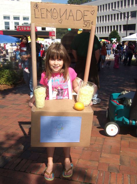 2008. Lemonade Stand costume.  Fairly easy to do.  Used a cardboard box for the base and wrapping paper rolls to go up to the sign.  Drilled through the bottom of the box for the cup and pitcher filled with yellow yarn.  The lemon is fake from Michaels.  The hardes part was to make it stay on without tipping forward or backyard.  We managed it by taking elastic and criss crossing it across her back and hooking it on the top and bottom of the box to stabilize. Halloween Costume Ideas Kids, Disney Family Costumes, Halloween Costumes Kids Homemade, Lemonade Stand Sign, Yellow Yarn, Duck Pins, Wrapping Paper Rolls, Homemade Halloween Costumes, Homemade Costumes