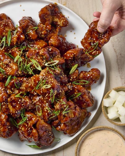 overhead shot of korean fried chicken, topped with sesame seeds and scallions, on a round white platter, with a hand coming in and grabbing a piece of chicken off of the platter, and a small bowl of pickled radish and kimchi ranch to the right of the platter Korean Dinner Ideas, Chicken Recipes Honey, Korean Dinner, Korean Fried Chicken Recipe, Honey Baked, Korean Fried Chicken, Rice Ingredients, Chicken Bites, Food History