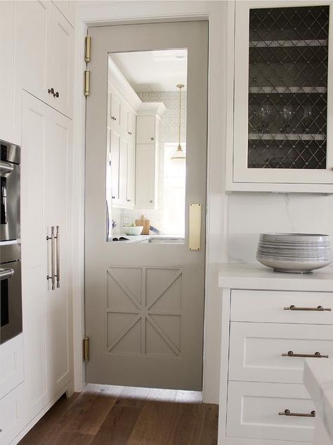 A gray pantry door in Sherwin Williams Anew Gray is fitted with a glass panel and positioned adjacent to floor-to-ceiling light gray shaker cabinets painted in Benjamin Moore Edgecomb Gray and finished with Armac Martin Queslett Hardware. Anew Gray Sherwin Williams, Grey Painted Kitchen, Greige Kitchen, Anew Gray, Greige Paint Colors, Door Paint Colors, Kitchen Paint Colors, Sherwin Williams Paint Colors, Kitchen Cabinet Colors