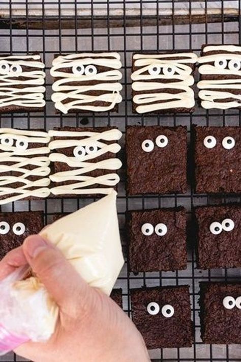 Spooky Mummy Brownies a Halloween Treat for the little ghosts and goblins in your home. Made with an Easy Brownie Recipe hand mix and enjoy. Homemade brownie recipe, and decorate with white chocolate and candy eyes for this fun and tasty dessert recipe. | mummy brownies halloween | halloween desserts mummy brownies | how to make mummy brownies | halloween mummy brownies ideas | halloween brownies recipes Halloween Party Brownies, Brownie Graveyard Halloween, Halloween Mummy Brownies, Halloween Easy Baking Ideas, Halloween Desserts Brownies, Ghost Brownies Marshmallow, Halloween Treats Brownies, Halloween Desserts Easy Cupcakes, Halloween Ghost Brownies