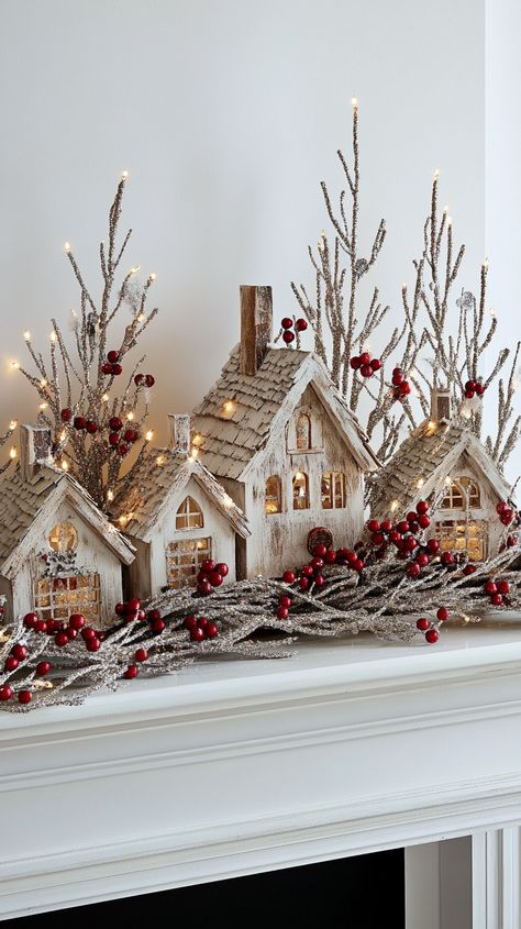 Christmas scene on a fireplace mantle featuring intricately carved wooden houses and trees with twinkling lights and red berries. Mantle Village Display, Nativity Christmas Decor Ideas, Natural Christmas Mantle Ideas, Winter Decor Ideas For The Home Living Rooms, Decorating Lanterns For Christmas, Xmas Decorations Living Room, Christmas Decor Ideas For Living Room Cozy, Accent Lighting Living Room, Christmas Decor Ideas For Living Room