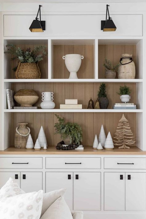 We wanted to share with you all a few of our favorite designer-approved holiday decor picks that will make your house look festive and cheery! For this holiday shelf styling, we added white ceramic trees, festive holiday plants, and lots of neutral shelf decor. Head to our blog for all of the best neutral holiday decor ideas! Christmas Shelf Styling, Kitchen Cabinets Living Room, Holiday Fireplace Decor, Shelf Styling Living Room, Christmas Shelves, Painted Built Ins, Styled Shelves, Mindy Gayer Design, Cabinets Living Room