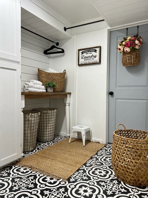 Laundry room with stenciled tile, white shiplap and board and batten, wood and white folding table, gray door, and woven baskets. Decorating With Lavender, Shiplap Laundry Room, Two Panel Door, Cottage Mudroom, Laundry Folding Tables, Laundry Room Tables, Laundry Room Folding Table, Farmhouse Laundry Room Ideas, Laundry Room Decorating