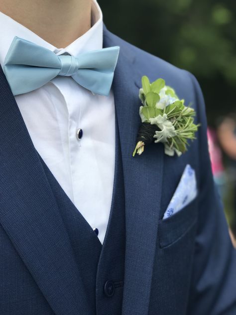 Navy blue suit and vest with light blue bow tie. Silver crested navy shirt studs and light blue white and navy blue patterned pocket square. Also a beautiful succulent boutonnière. Light Blue Tie Suit, Blue Suit Grey Waistcoat, Tuxes Wedding, Navy Tuxedo Wedding, Blue Suit Bow Tie, Suit And Vest, Slate Blue Suit, Navy Blue Tux, Bow Tie Outfit