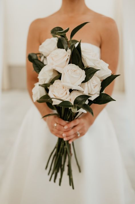 A simple and classic bridal bouquet with white roses and touches of italian ruscus. Bouquet With White Roses, Long Stem Bouquet, Classic Bridal Bouquet, Classic Wedding Flowers, White Rose Bridal Bouquet, Winter Bridal Bouquets, White Rose Wedding Bouquet, Elegant Wedding Bouquets, Simple Wedding Bouquets