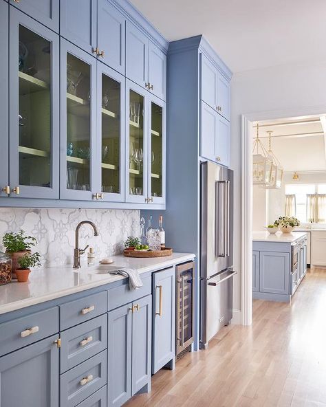 Periwinkle blue kitchen features blue cabinets donning brass hardware and finished with a small prep sink and a polished nickel gooseneck faucet mounted beneath glass front cabinets stacked under blue overhead cabinets. Tori Rubinson, Blue Beadboard, Beadboard Trim, Dreamy Kitchens, Style Pantry, Blue Kitchen Cabinets, Glass Front Cabinets, Blue Cabinets, House On The Rock