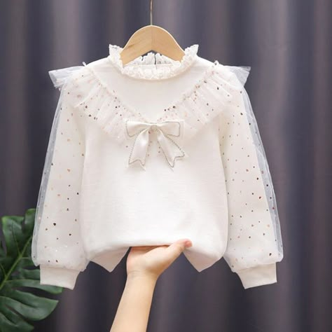 The White Bow Lace Long Sleeve Shirt is a beautiful and stylish pullover top designed for kids between the ages of 3 to 12 years. This shirt is perfect for the spring and autumn seasons, providing both comfort and elegance for toddler and teen girls. The shirt features delicate lace detailing and a charming bow accent, adding a touch of sophistication to the design. The long sleeves make it suitable for cooler weather, and the soft cotton fabric ensures a cozy and comfortable fit for all-day wea White Blouse With Bow, Lace Long Sleeve Shirt, Kids Activewear, Kids Dress Wear, Shirt Girl, Girls Blouse, Lace Long Sleeve, Children Clothes, White Bow