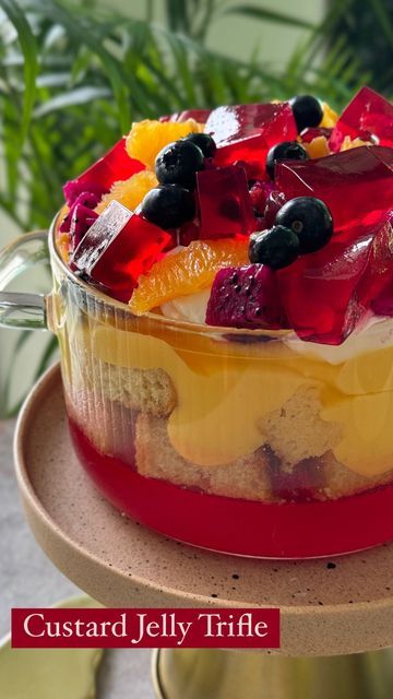 Sneha Singhi Upadhaya on Instagram: "Jelly Custard Trifle
This trifle is the perfect dessert to make your friends/siblings/family feel special on any occasion. It comes together so easily & looks absolutely stunning. Let’s make it. 

Wearing @prakritijaipur 

Serves 6-8
1 packet jelly (I’ve used strawberry flavoured jelly)
500 mls hot water
1 tbsp agar agar
Mix the jelly & agar agar well in your trifle bowl. Pour in the hot water & whisk till all the jelly crystals are dissolved. Transfer a little bit of the mixture in another dish (for garnish). Let this set in the fridge for 30-40 minutes or until the jelly is completely set.

Custard
6tbsp custard powder
1/4 cup sugar
300 ml milk
Heat the milk, sugar & custard till it thickens whisking continuously to avoid burning. Keep aside & let it Custard Trifle, Jelly Custard, Cup Of Fruit, Orange Pomegranate, Jelly Crystals, Dessert To Make, Trifle Bowl, Vanilla Sponge Cake, Custard Powder