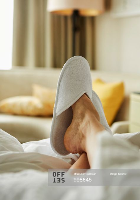 Person's foot with bedroom slipper resting on bed in hotel room stock photo - OFFSET Bedroom Slippers, Visa Gift Card, Hotel Room, Hotels Room, Stock Photography, Slippers, Illustrations, Hotel, Bedroom