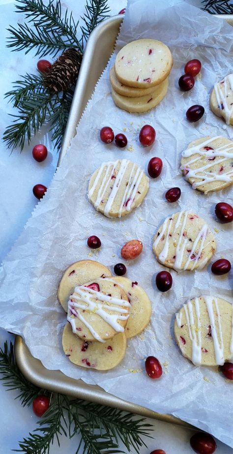 A tray of fresh-baked Lemon Cranberry Slice Cookies sits on top of a white, marble counter that give the appearance of fresh snow. Fresh evergreens, pine cones and cranberries frame the tray. Bright and festive! Lemon Cranberry Cookies Recipes, Lemon Cranberry Recipes, Cranberry Lemon Shortbread Cookies, Lemon Cranberry Shortbread Cookies, Lemon Cranberry Sugar Cookies, Cranberry Cookies Fresh Cranberries, Cranberry Lemon Cookies, Lemon Christmas Dessert, Lemon Cranberry Cookies