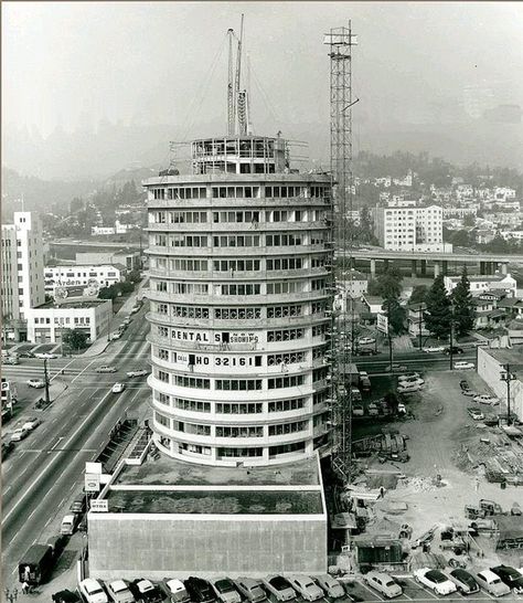 Capitol Records under construction in 1955. The wide curved awnings over windows on each story and the tall spike emerging from the top of the building resemble a stack of records. The blinking light atop the tower spells out the word "Hollywood" in Morse code, and has done so since the building's opening in 1956 -- Architect: Welton Becket Awnings Over Windows, Ca History, Hollywood Vintage, Architectural Firm, California History, Los Angles, Vintage Los Angeles, Capitol Records, Vintage California