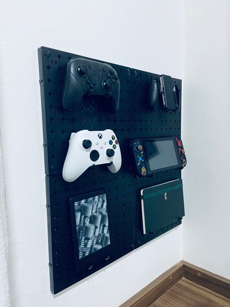 A picture of a pegboard holding some things like an xbox and nintendo controller and a sketchbook Pegboard Nintendo Switch, Mens Gamer Bedroom Ideas, Video Game Corner Ideas, Gamer Pegboard, Fortnight Bedroom Ideas, Boys Game Bedroom, Pegboard Gaming Setup, Playstation Bedroom, Teen Gaming Bedroom