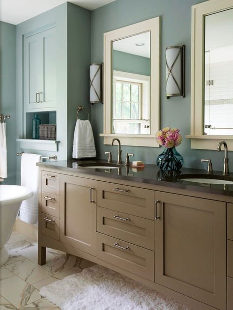 Taupe + Dusty Blue + Off-White-Muted blue walls surround this bathroom with calming energy. The vanity was given a fresh coat of sandy-brown paint, which echoes the muted hue of the bathroom's walls. Warm off-white furnishings, such as the marble floor and the painted mirror frames, blend well into the room's relaxing aesthetic Colorful Bathrooms, Best Bathroom Colors, Sophisticated Bathroom, Bathroom Color Schemes, Bathroom Color, White Vanity Bathroom, Brown Walls, Up House, Stylish Bathroom