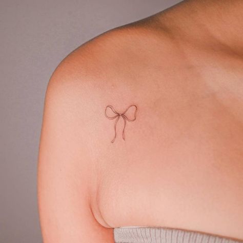 Fine line style ribbon tattoo placed on the shoulder. Shoulder Bow Tattoo, Bow Shoulder Tattoo, Bow Tattoo Shoulder, Fine Line Ribbon Tattoo, Fine Line Bow Tattoo, Line Fashion, Ribbon Tattoos, Bow Tattoo, Cute Tattoos For Women