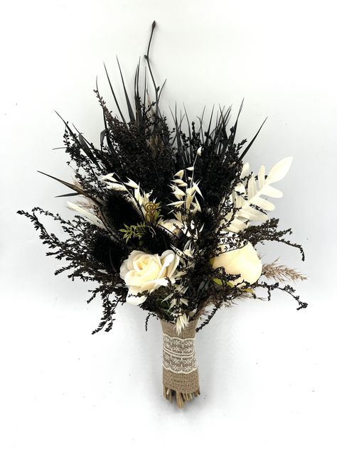 Gothic Wedding Bouquet: Black Flower and White Rose Arrangement Delve into the realm of the romantic and mysterious with our Gothic Wedding Bouquet. This meticulously curated arrangement of black flowers and white roses is the epitome of Gothic elegance, designed for the bride with a penchant for the unconventional. Unique Black Bouquet: The allure of the dark blossoms is undeniable. The rich, black flowers are hand-selected for their velvety petals and deep hue, providing a captivating contrast to the traditional white bridal gown. This unique black bouquet is not only a beautiful accessory but a bold statement of individuality. Elegant White Rose Bridal Accessory: White roses, synonymous with love and purity, are interwoven with the dark blossoms creating a surreal yet elegant display. T Flowers To Go With Black Dress, Black And White Boho Wedding, Black And White Flower Bouquet, Dark Wedding Bouquet, Black And White Wedding Bouquet, Black Flowers Bouquet, Black Wedding Bouquet, Alternative Wedding Flowers, Spooky Bouquet