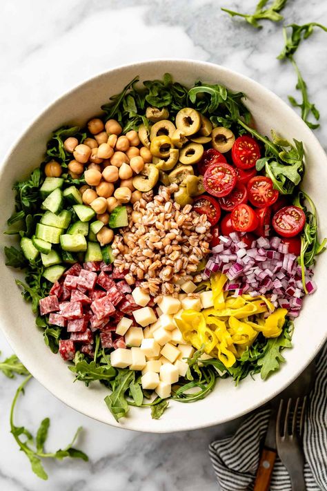 This Hearty Italian Farro Salad is like antipasto pasta salad, made with healthy whole grains! Toss hearty farro with soppressata, asiago cheese, olives, pepperoncini, arugula, & a zingy Italian dressing for an easy, satisfying grain salad. A beautiful light summer dinner & the perfect make-ahead side for picnics or BBQs! (Easily vegetarian & dairy-free) #italianfarrosalad #farrorecipes #farrosalad #grainsalad #grainsaladrecipes #healthygrainsalads #saladrecipes #saladideas #saladsforparties Summer Farro Salad, Toasted Farro Salad, Arugula And Farro Salad, Favorite Greek Farro Salad, Roasted Vegetable Farro Salad, Farro Salad With Roasted Root Vegetables, Grain Salad Recipes, Light Summer Dinners, Farro Recipes