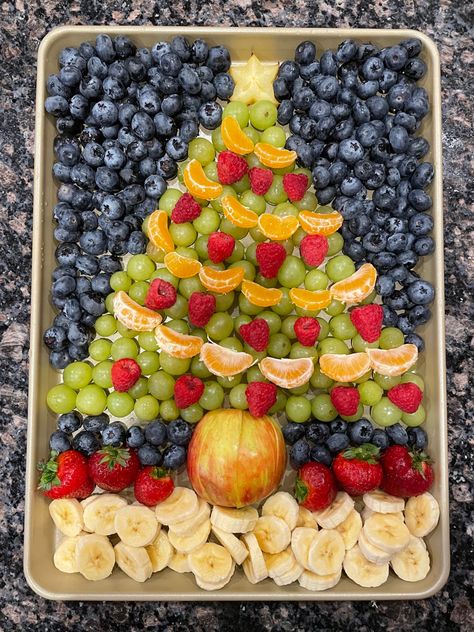 A colorful christmas tree shaped fruit platter on a silver baking tray. A star fruit slice forms the star on top of the tree, and mandarin oranges are strung together like streamers going around the tree. Fruit Plate Christmas, Veggie Christmas Platter, Fruit Christmas Tree Platter, Christmas Tree Fruit Platter, Christmas Fruit Trays, Fruit Platter Christmas, Christmas Tree Fruit Tray, Fruit Platers, Holiday Fruit Platter