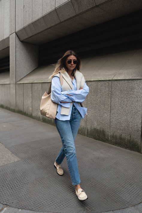 Emma Hill wears blue striped shirt, beige ribbed jumper over shoulders, mid wash straight leg jeans, beige suede loafers. Spring outfit Vionic Loafers Outfit, Beige Loafers Outfit Women, Beige Loafers Outfit, London Wardrobe, Loafer Outfits Women, Loafers Outfit Women, Blue Striped Shirt Outfit, Spring Uniform, Loafer Outfits