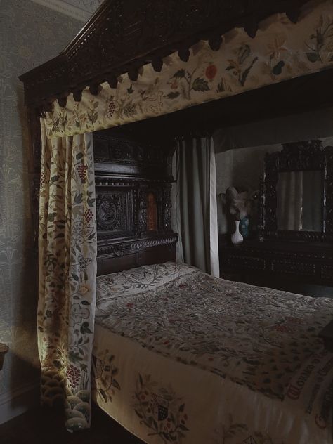 A dark room showcasing a tudor (1500s) style four poster bed. The bedding is a cream colour with floral embroidery. The bed is made neatly and the wooden frame of the bed is dark and has floral carvings on the headboard. Mary Tudor Aesthetic, Era Medieval Aesthetic, Tudor Era Aesthetic, Tudor Aesthetic Wallpaper, The Tudors Aesthetic, 1500s Aesthetic, Tudor History Aesthetic, Tudor Aesthetic, Baker Aesthetic