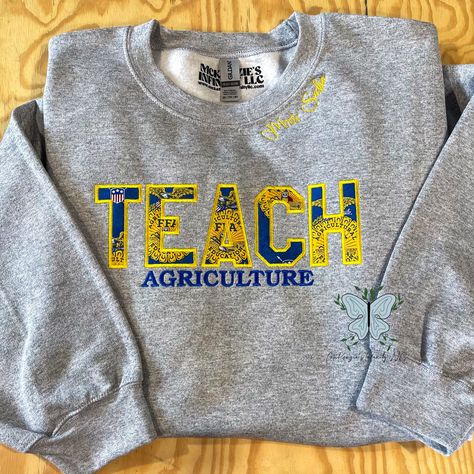 Inspire success with our TEACH Agriculture FFA Personalized Embroidered Crewneck Sweatshirt! Made with pride and precision, this customizable sweatshirt showcases your passion and dedication to the FFA organization. Stay warm and represent your commitment to agriculture education in style. THIS IS A PHYSICAL PRODUCT. CREWNECK IS UNISEX. CREWNECK IS EMBROIDERED. Ffa Jacket Shadow Box Ideas, Ag Teacher Gift Ideas, Ffa Advisor Gifts Ideas, Ag Classroom Decorations, Ffa Apparel, Ffa Teacher, Ag Teacher Outfits, Reverse Embroidery, Agriculture Classroom