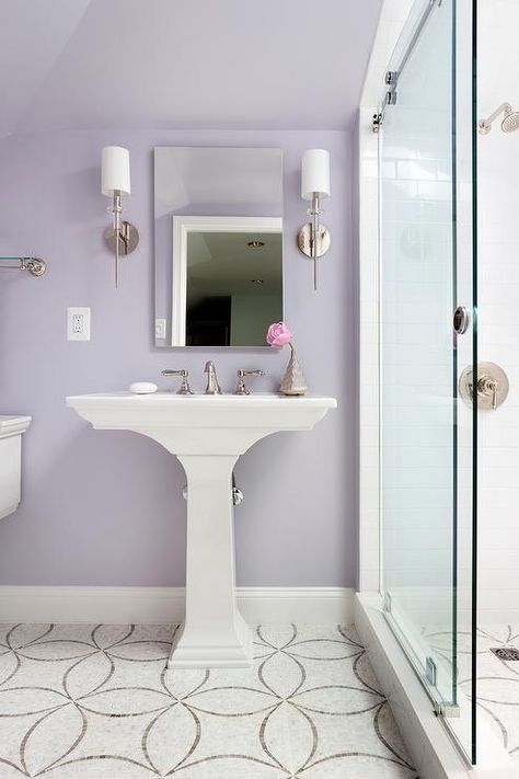 Ann Sacks Chrysalis Tiles lead to a white pedestal sink placed against a lavender wall and fitted with a polished nickel faucet kit located beneath a frameless medicine cabinet flanked by Hudson Valley Lighting Amherst Sconces mounted on a wall beside a walk in shower finished with sliding glass doors and a polished nickel shower kit mounted to white surround tiles above gray and white mosaic wall tiles in this gorgeous girl's bathroom. Lavender Bathroom Walls, Purple Bathroom, Lavender Bathroom Decor, Pedestal Sink Ideas, Lilac Bathroom, Bathroom Colors Gray, Lavender Bathroom, Pastel Bathroom, Purple Bedroom Decor