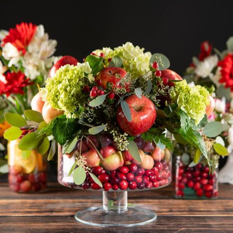 It’s always nice to have a floral arrangement displayed on the table to enjoy the colors of the season, but why not add a little extra flair with a dash of seasonal produce? We put together a few ideas of how to incorporate this season’s produce in a beautiful centerpiece. Floral Arrangement With Vegetables, Fruit Basket Centerpiece Ideas, Fruit Flower Centerpiece, Floral Arrangements With Fruit, Pomegranate Floral Arrangement, Produce Centerpieces, Apple Centerpiece Ideas, Fruit Centerpiece Ideas, Fruit And Flower Arrangements