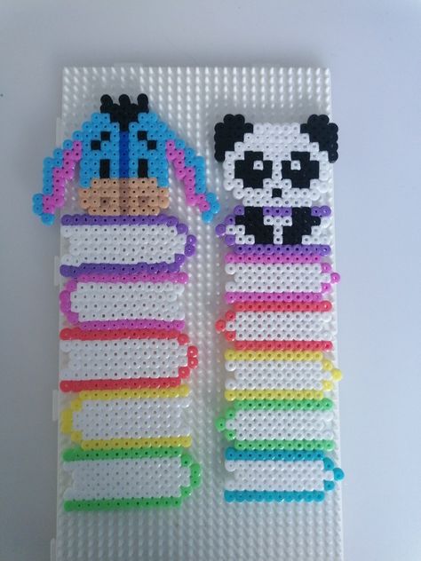 Handmade bookmarks from perler beads. Left one is a stack of books with eeyeore on top. Right one is a stack of books with a panda on top Pearler Beads Panda, Pyssla Ideas Bookmark, Hama Beads Bookmarks, Hama Beads Bookmark Ideas, Perler Art Ideas, Cute Perler Bead Bookmarks, Disney Perler Beads Ideas, Iron Beads Bookmark, Book Mark Perler Beads