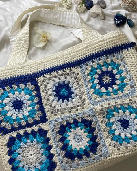 In the photo there is a crochet bag with granny squares in the colors blue, white and grey. The bag itself is white. There are also some crystals and shells for decoration. Crochet Laptop Case, Granny Square Crochet Bag, Square Crochet Bag, Square Crochet, Granny Squares, Crochet Granny, Laptop Case, Granny Square, Crochet Bag