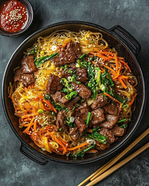 Japchae is a traditional Korean dish made with sweet potato glass noodles, known for their uniquely chewy texture and lightly sweet flavor. In this recipe, the noodles are stir-fried with tender slices of beef, fresh vegetables, and seasoned with a savory blend of soy sauce and sesame oil, creating a […] Japchae Noodles Recipe, Korean Stir Fry Noodles, Korean Beef And Noodles, Easy Japchae Recipe, Korean Glass Noodles Recipe, Delicious Korean Food, Sweet Potato Glass Noodles Recipe, Korean Healthy Food, Glass Noodle Recipes