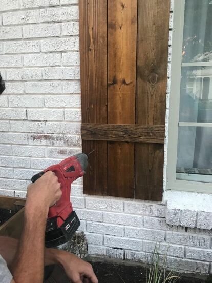 My husband and I looked for different ways to hang our DIY wood shutters onto our brick house, and there were quite a few different options that we came across. It got slightly confusing, so I thought I’d share what we decided to do and what worked for us.I’d like to note that we are not pros, but this is what we found to work for us.   We started by holding the shutter up where we were planning to hang it on the house. From there, we marked the shutter where the mortar line on the hou… White Brick Wood Shutters, How To Hang Wood Shutters On Vinyl Siding, How To Hang Shutters On Brick, Shutters For Brick House, Cedar Shutters On Brick, Diy Wood Shutters Exterior, Shutters On Brick House, Diy Shutters Exterior, Exterior Shutters On Brick