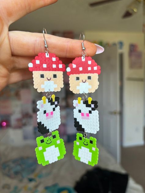 Squishmallow earrings made out of mini perler beads! Oogie Boogie Beaded Earrings, Mini Perler Bead Hello Kitty Earring, Perler Sanrio, Round Perler Bead Patterns, Perler Beads Earrings Ideas, Cartoon Perler Beads, Squishmallow Kandi, Squishmallow Perler Beads, Squishmallow Perler