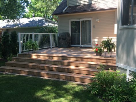 Check with your city’s building code before proceeding. We needed to replace the railings around our deck. During the process of preparing the deck to receive the new aluminum railings we like the look of the long side of the deck without railings. Our son suggested that we eliminate the railings on the long side by extending the steps the full length of that side. So, we constructed three 16” deep treads the full length of the long side of the deck. We’re delighted with the results. Railing On One Side Of Porch, Front Deck No Railing, Deck With Long Steps, Deck With Railing On One Side, Deep Deck Steps, 3 Tier Deck Design, Deck With Steps Down To Patio, Deck No Railing Ideas, Deck On Back Of House