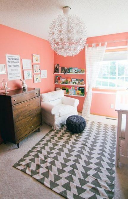 a cheerful grey and coral nursery with coral walls, a printed rug, a stained sideboard, a cool chandelier and whiet touches Coral Painted Walls, Coral Nursery Decor, Coral Baby Girl Nursery, Girl Nursery Colors, Baby Room Boy, Girls Room Paint, Nursery Color Scheme, Coral Nursery