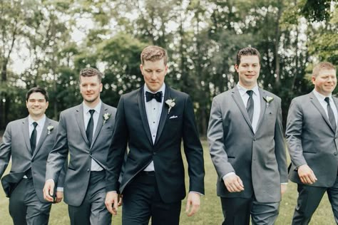 Groom wearing a black tux surrounded by groomsmen wearing grey suits on wedding day Grey Tux Wedding, Charcoal Suit Wedding, Groomsmen Attire Grey, Table Centre Pieces Wedding, Groomsmen Attire Black, Charcoal Suits, Centre Pieces Wedding, Black Tux Wedding, Classic Black Suit