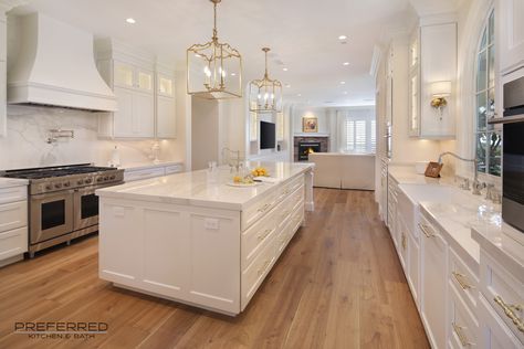 White gorgeous kitchen with golden wood floors that match the gold accents in the space created by the pendants and hardware. White And Golden Kitchen Modern, Kitchen Wood Flooring Ideas White Cabinets, Kitchen Ideas White And Gold, White And Golden Kitchen, White Kitchen Gold Accents, White Kitchen With Wood Floors, White Kitchen Gold Hardware, White Kitchen With Gold Hardware, White Kitchen With Gold Accents