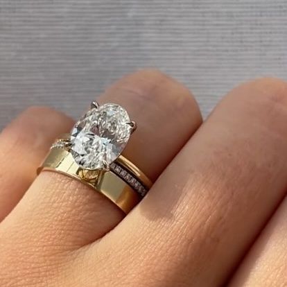 Her Rock | Lab Grown Diamonds on Instagram: "How would you rate this ring stack? On a scale of 1-10, we give this a BIG 10 points for modern luxuriousness✨ Our best selling setting “The Slim” in 14k yellow gold holds a gorgeous oval cut G.I.A. Certified lab diamond. Stacked with our Cigar Band and Slim Pave Wedding Band, the 3 make a show-stopping grouping. Let’s chat engagement rings! Use the link in our bio to schedule your ring appointment💍 #ovalengagementring #ovalcutdiamond #ovalcut #haileybieber #cigarband #weddingband #goldrings #pavering #diamondring #labdiamonds" Slim Band Engagement Ring Gold, Classic Wedding Ring Stack, Oval Engagement Ring Gold Setting, Chunky Wedding Band Stack, Oval Solitaire Engagement Ring Stack, Solitaire Engagement Ring And Wedding Band, Round Diamond Ring Stack, Pave Engagement Ring Stack, Modern Wedding Ring Stack