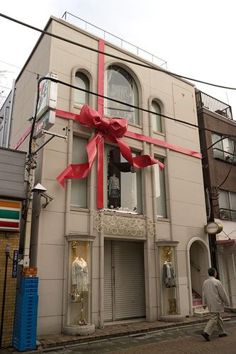 Building Christmas Decoration, Christmas Building Decorations, Giant Christmas Bow On House, Red And White Christmas Window Display, Giant Ribbon Bow, Christmas Red Bow Front Doors, Bow Building, Big Red Bows Christmas, Ribbon Wrapping