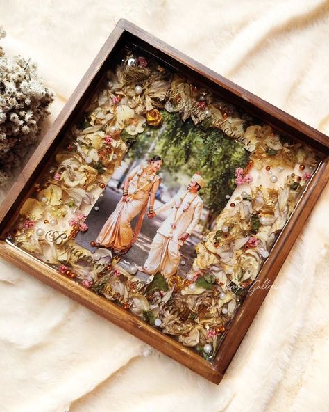 My client Abhishek wanted to gift his friends our trending frames and placed order for the frames as a post-marriage gift to the newly weds 🎁 Upon receiving fresh garlands immediately after the event, we could do proper drying of the flowers with utmost care & attention. This frame is really special , as I tried to incorporate cute elements to compliment the couples photo. And that's how the frame turned into 💕 This is one of the finest frames that I created and loved each bit of the pr... Resin Frames For Couples, Wedding Photo Frame Ideas, Resin Art Photo Frame, Resin Gift Ideas, Varmala Preservation, Resin Gifts, Fresh Garlands, Marriage Gift, Presents Birthday